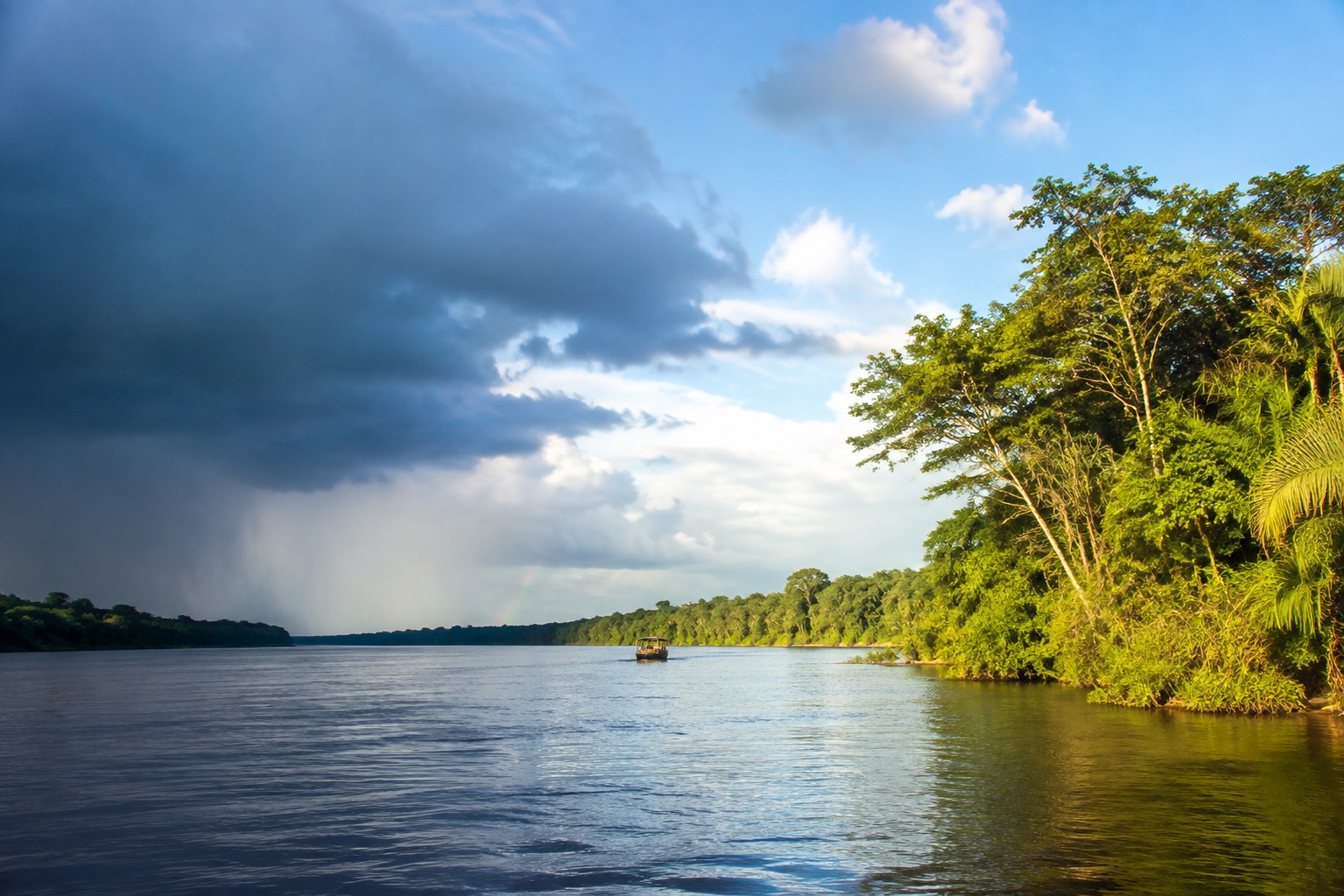 A rainforest river in Suriname under a sky of rain and sunshine